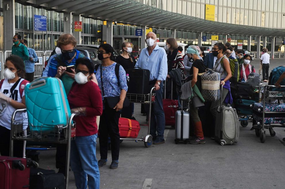 PHOTO: Foreign nationals wearing face masks line up outside the departure terminal of the Netaji Subhash Chandra Bose International Airport in Kolkata, India, March 31, 2020. 