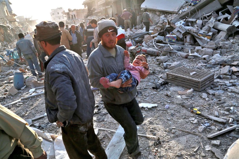 PHOTO: A Syrian man carries a child following a reported airstrike on the rebel-held town of Atareb in Syria's northern Aleppo province, Nov. 13, 2017.