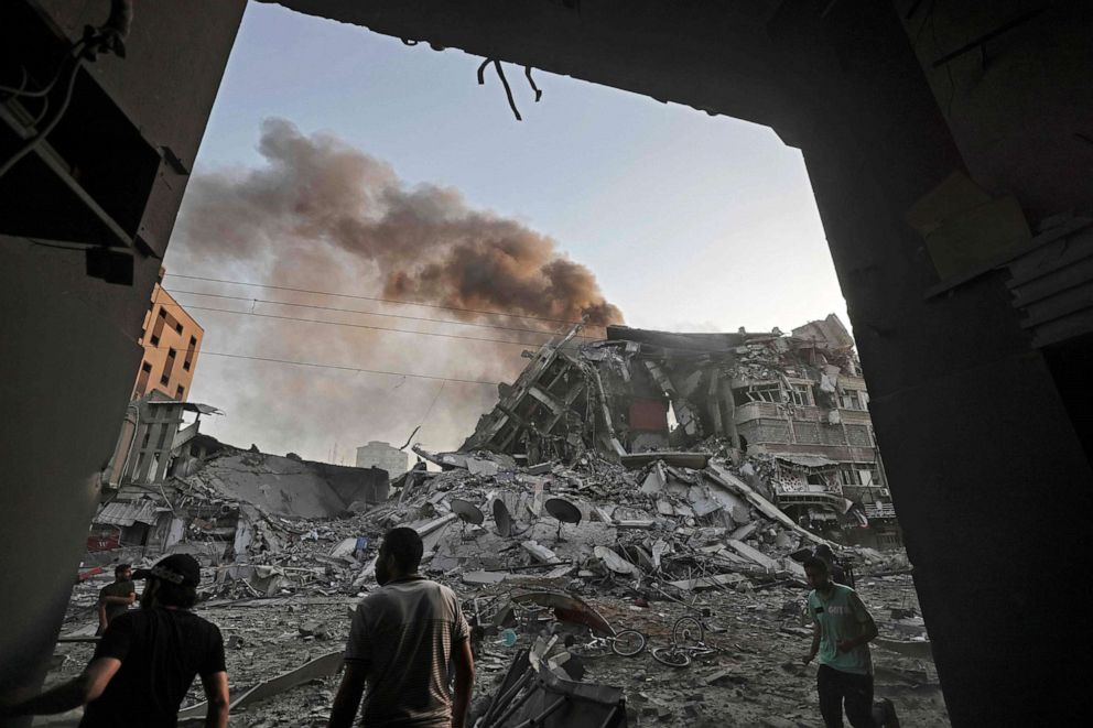 PHOTO: People gather in front of the rubble of the Al-Sharouk tower that collapsed after being hit by an Israeli air strike, in Gaza City, May 12, 2021.