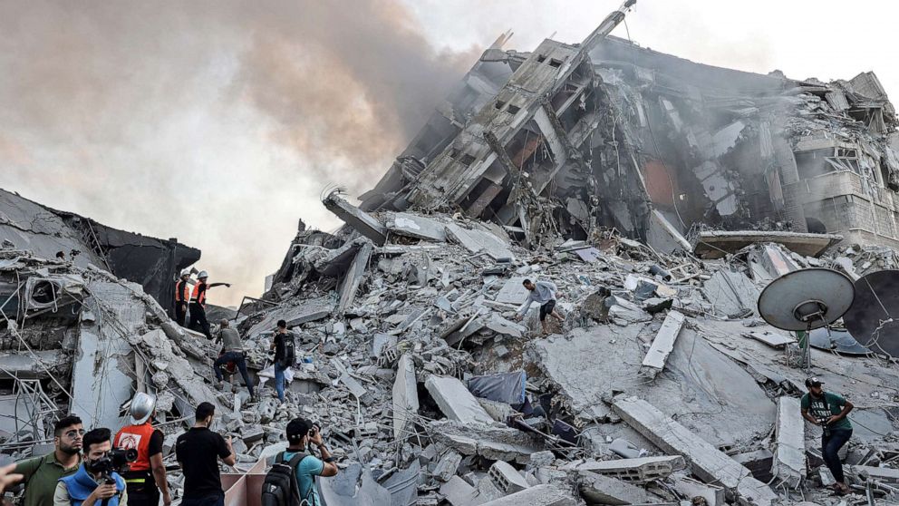PHOTO: People gather in front of the debris of Al-Sharouk tower that collapsed after being hit by an Israeli air strike, in Gaza City, on May 12, 2021.