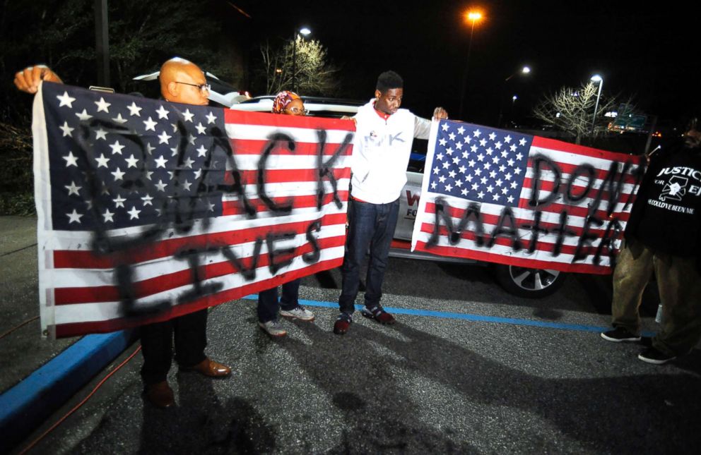 PHOTO: Activists protesting the police shooting of a black man in an Alabama shopping mall hold U.S. flags painted with the words "Black lives don't matter" in Hoover, Ala., Feb. 5, 2019.