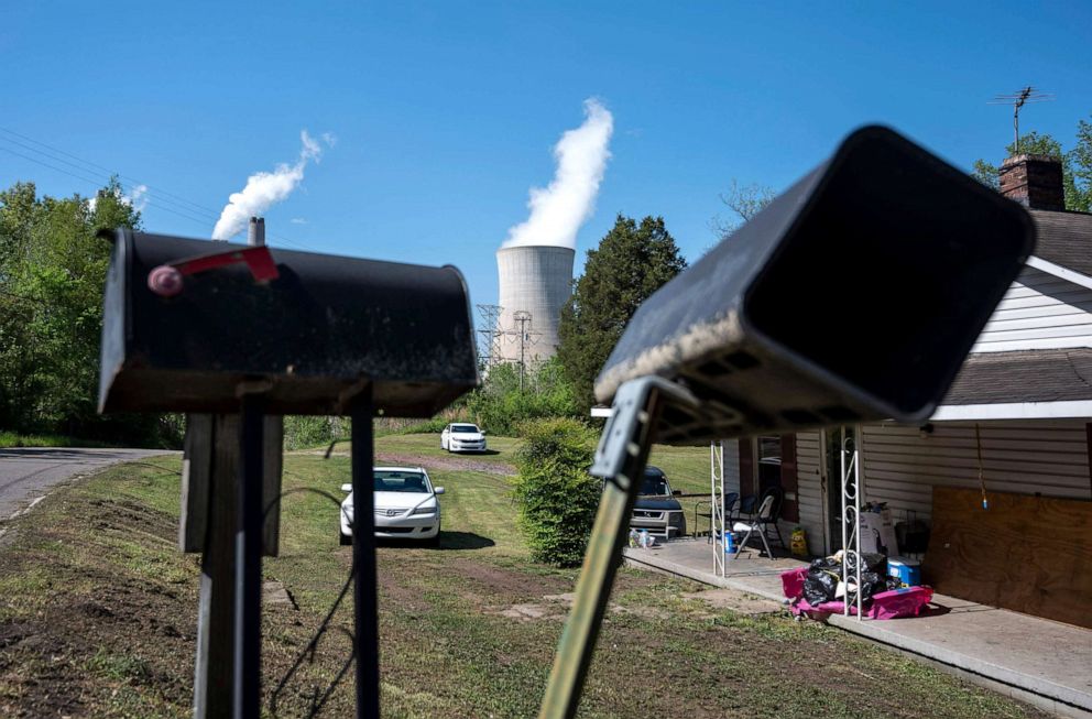 PHOTO: Cars are parked in front of a home as steam rises from the Miller coal Power Plant in Adamsville, Alabama, April 11, 2021.