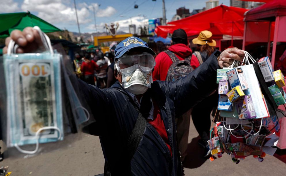 PHOTO: A man wearing a mask and goggles amid the coronavirus pandemic sells masks decorated with fake money at the annual Alasita Fair in La Paz, Bolivia, on March 24, 2021.