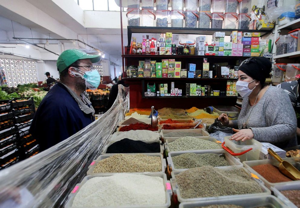 A vendor wearing a protective face mask serves a customer inside her shop, ahead of the Muslim holy month of Ramadan, amid concerns over the coronavirus disease (COVID-19), in Algiers, Algeria, April 19, 2020.Ramzi Boudina/Reuters