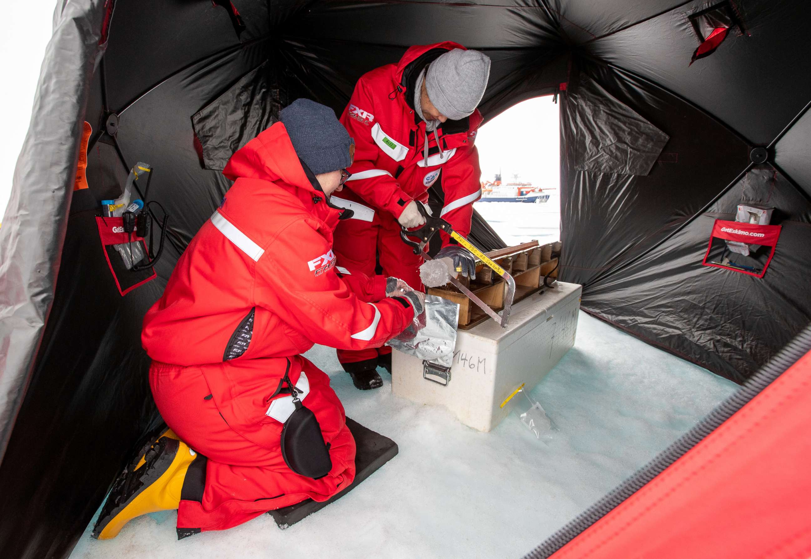 PHOTO: Dr. Allison Fong uses a saw to section off ice core samples in a tent in the Arctic.