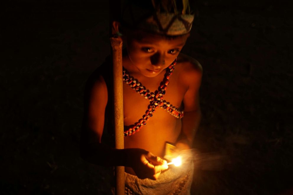 PHOTO: A young member of Peru’s Wachiperi indigenous group lights a match during a ceremony in the Amazon village of Santa Rosa de Huacaria.