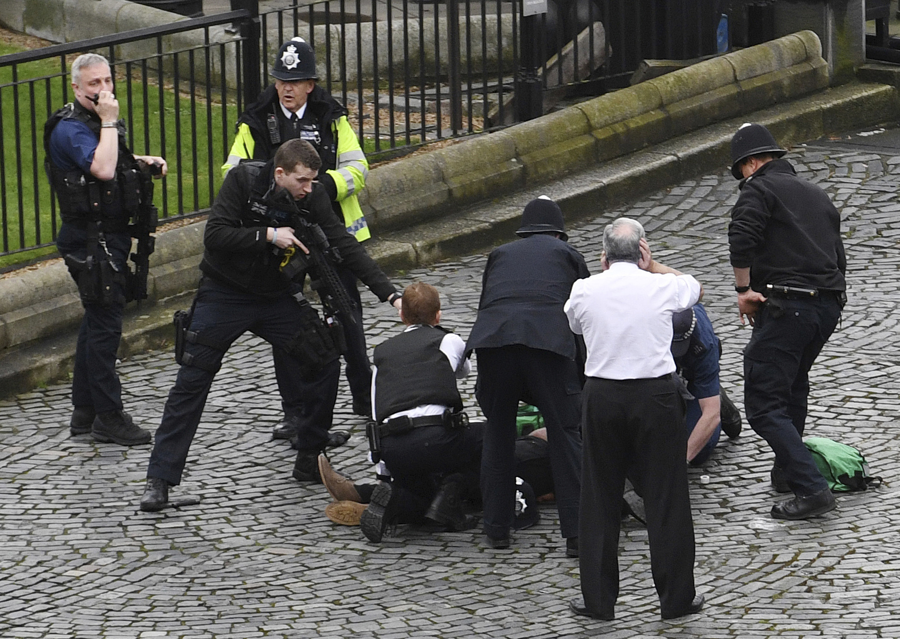 PHOTO: A policeman points a gun at a man on the ground as emergency services attend the scene outside the Palace of Westminster, London, March 22, 2017.