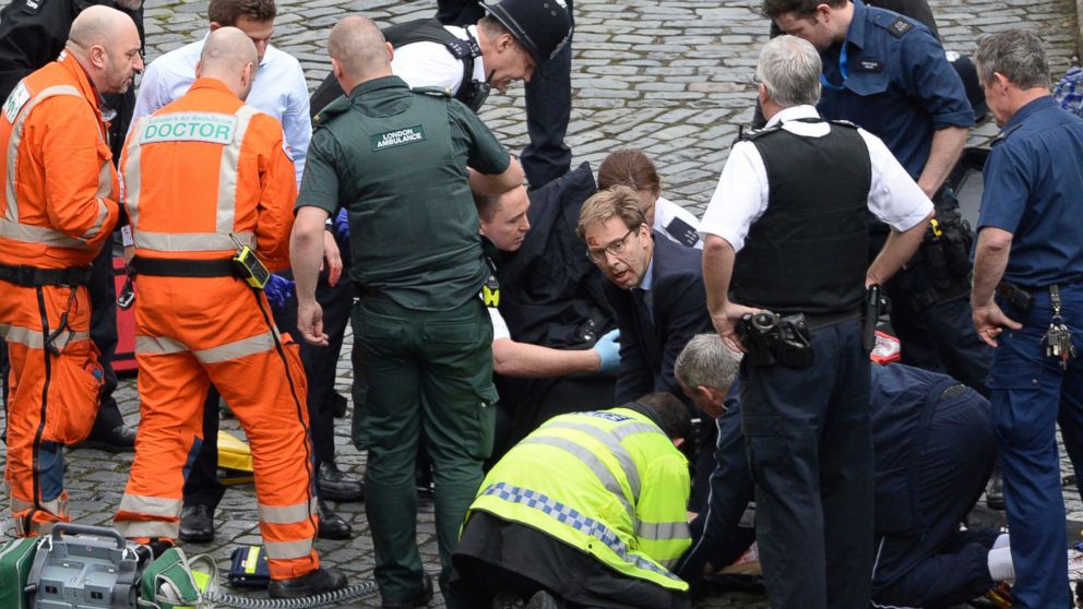 Conservative Member of Parliament Tobias Ellwood, center, helps emergency services attend to an injured person outside the Houses of Parliament, London, March 22, 2017.