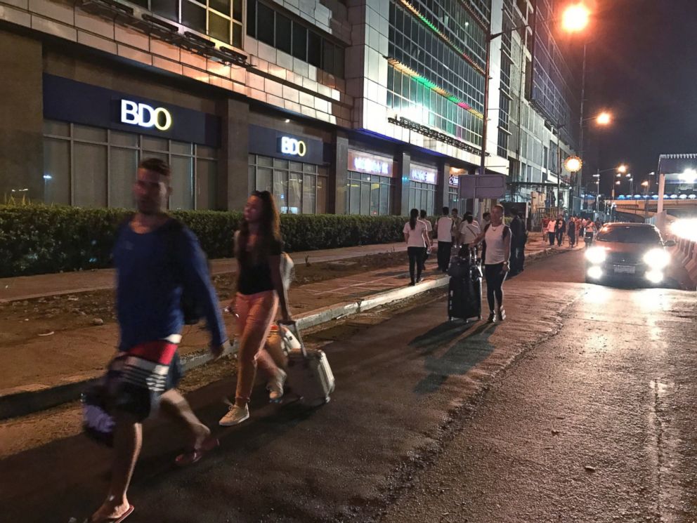 PHOTO: People walk with their luggage outside the Resorts World Manila complex, early Friday, June 2, 2017, in Manila, Philippines.