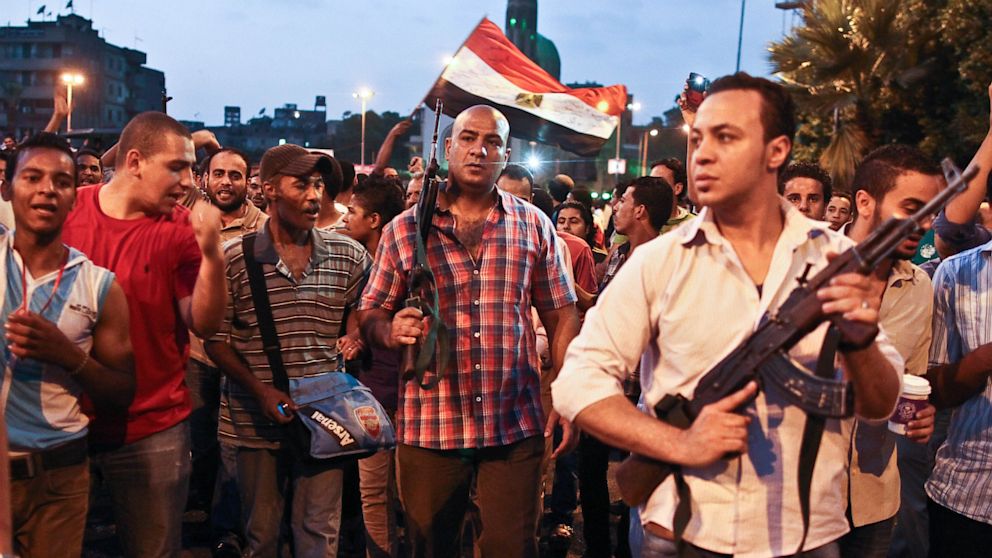 Plainclothes policemen walk with protesters opposed to Egyptian President Mohammed Morsi at the site of clashes with opposing protesters in the Kit Kat neighborhood of Giza, Egypt, Tuesday, July 2, 2013.