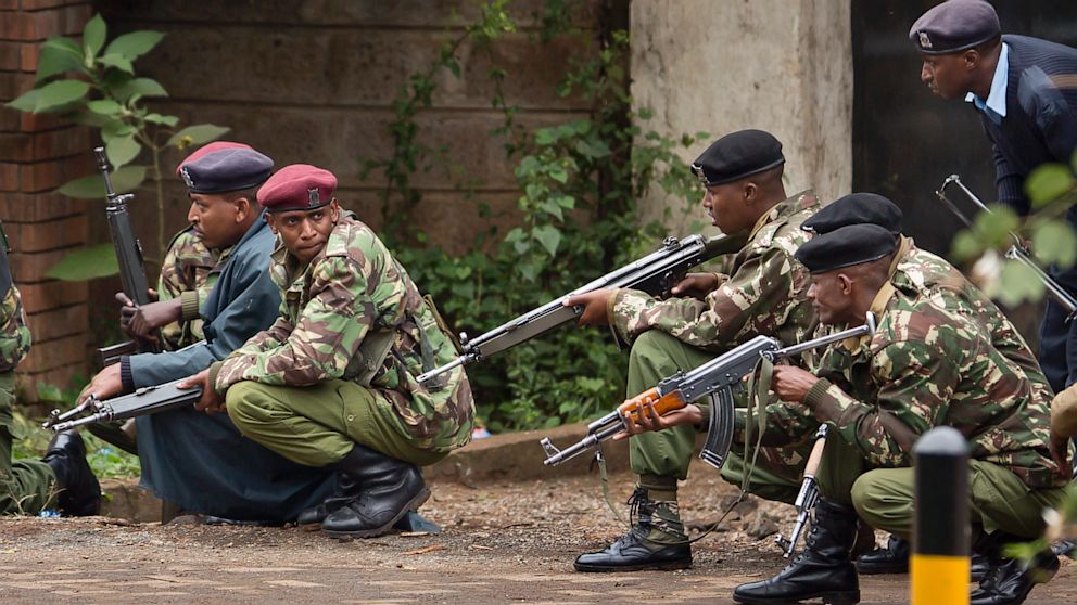 Armed police from the General Service Unit take cover behind a wall during a bout of gunfire outside the Westgate Mall in Nairobi, Kenya, Monday, Sept. 23, 2013.