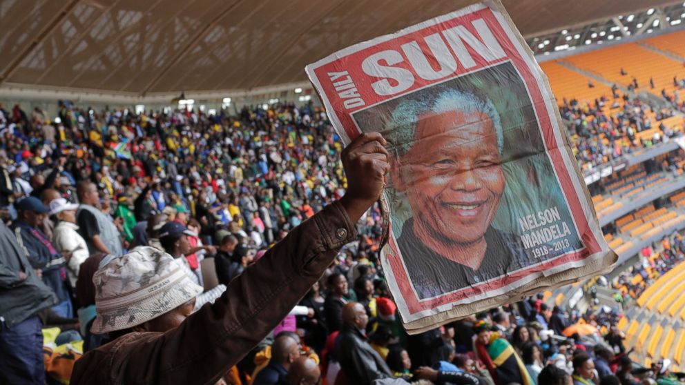A man  holds up an image of former South African president Nelson Mandela ahead of a memorial service at the FNB Stadium in Soweto, near Johannesburg, South Africa, Tuesday Dec. 10, 2013.