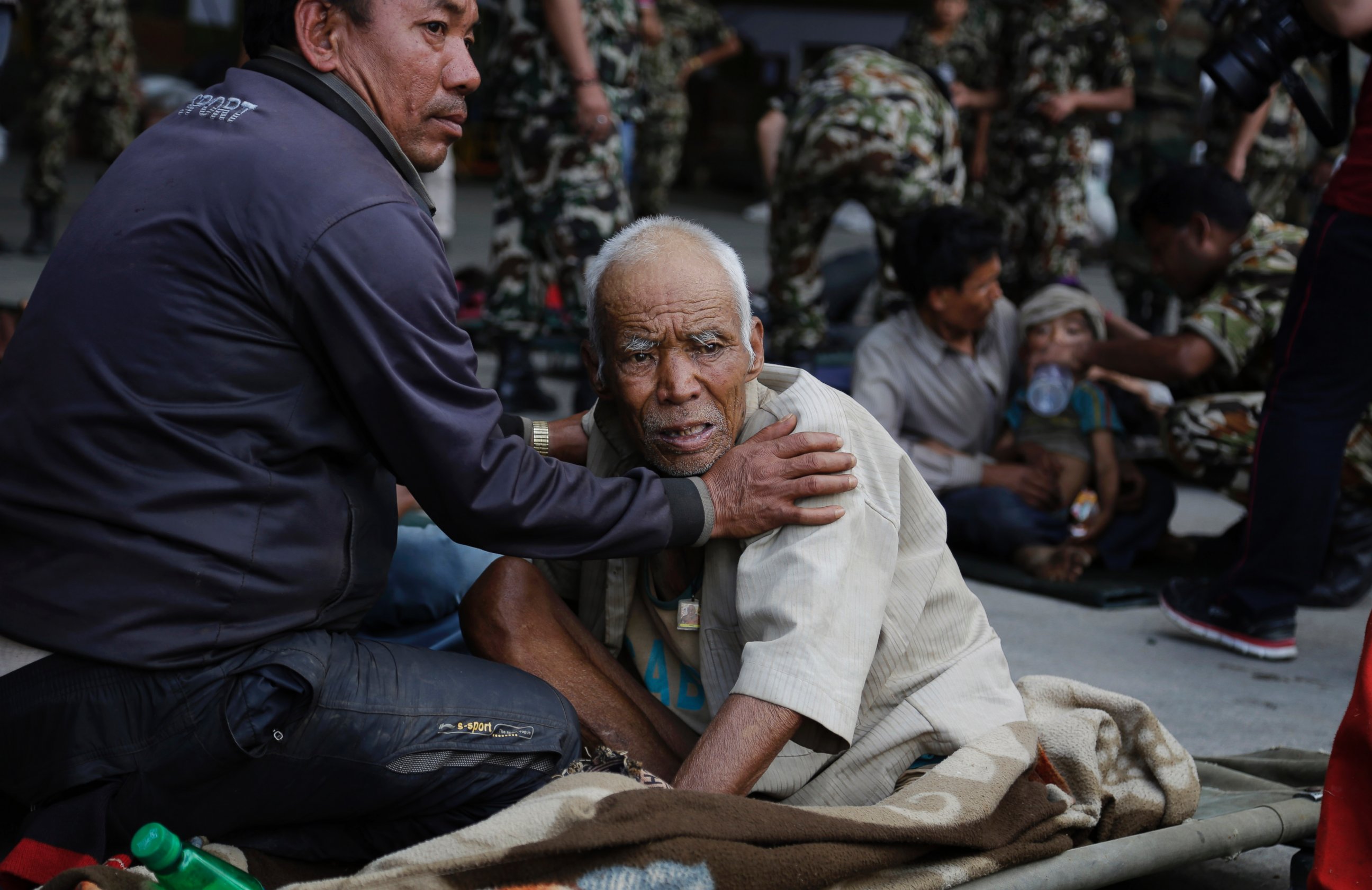 PHOTO: A Nepalese man attends to an elderly victim of Saturday's earthquake, while they wait for ambulances after being evacuated at the airport in Kathmandu, Nepal, April 27, 2015.