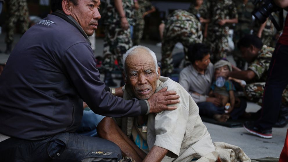 PHOTO: A Nepalese man attends to an elderly victim of Saturday's earthquake, while they wait for ambulances after being evacuated at the airport in Kathmandu, Nepal, April 27, 2015.