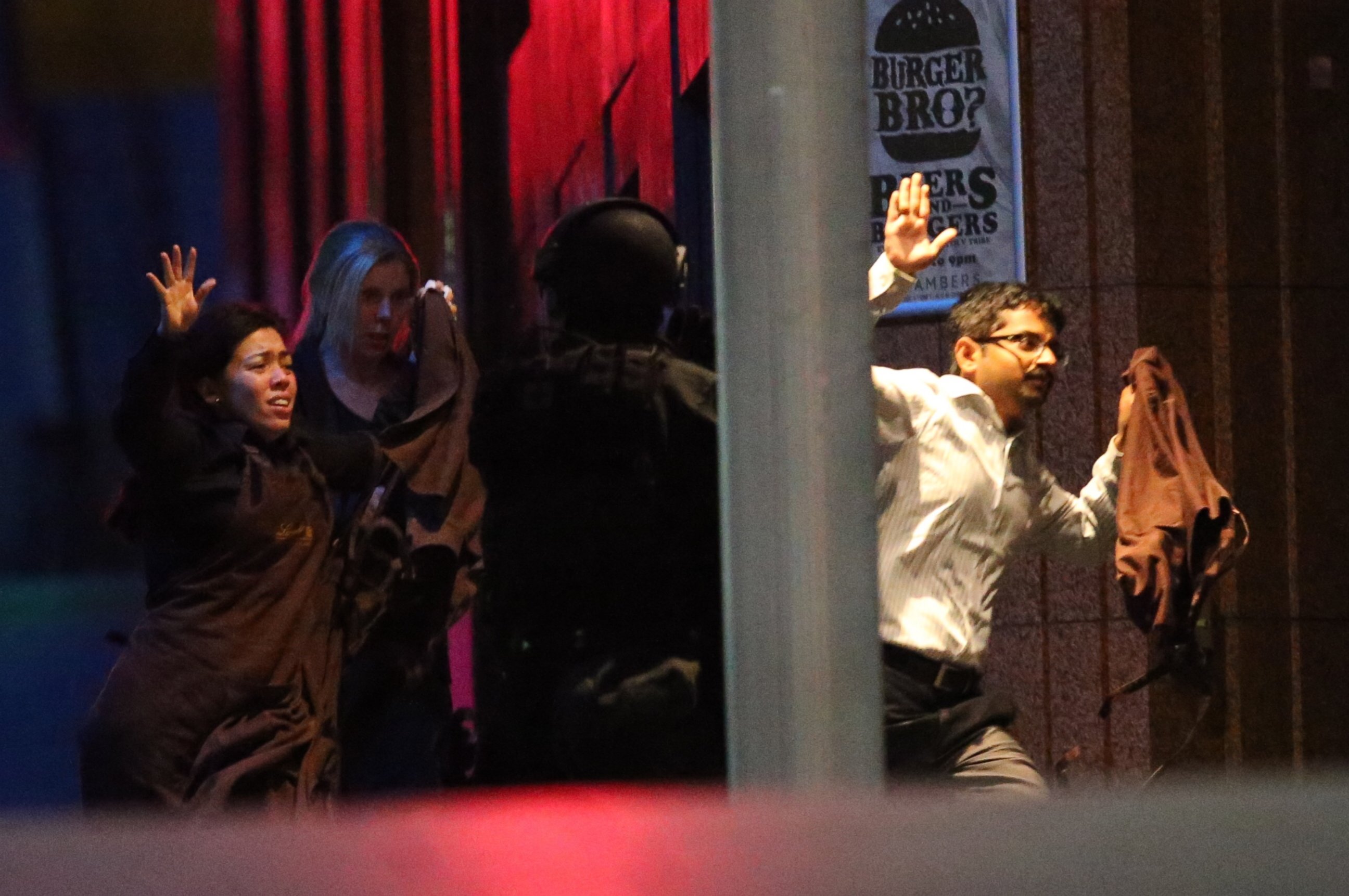 Hostages run toward armed tactical response police as they seek freedom from a cafe under siege at Martin Place in the central business district of Sydney, Australia, Dec. 16, 2014. 