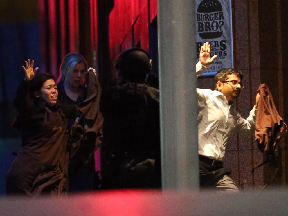 Hostages run toward armed tactical response police as they seek freedom from a cafe under siege at Martin Place in the central business district of Sydney, Australia, Dec. 16, 2014.