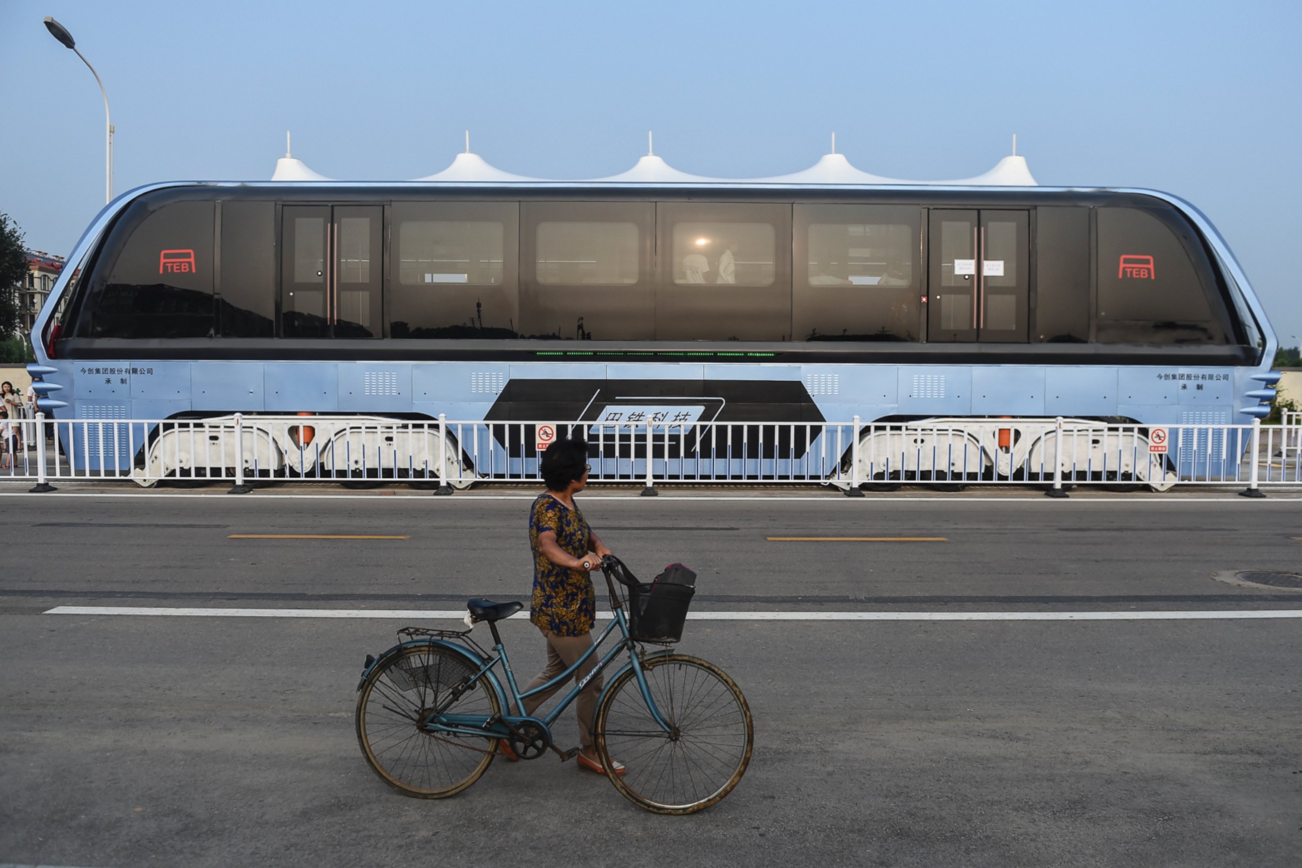 PHOTO: A woman walking with a bicycle looks at the Transit Elevated Bus TEB-1 in Qinhuangdao, north China's Hebei Province, Aug. 2, 2016.