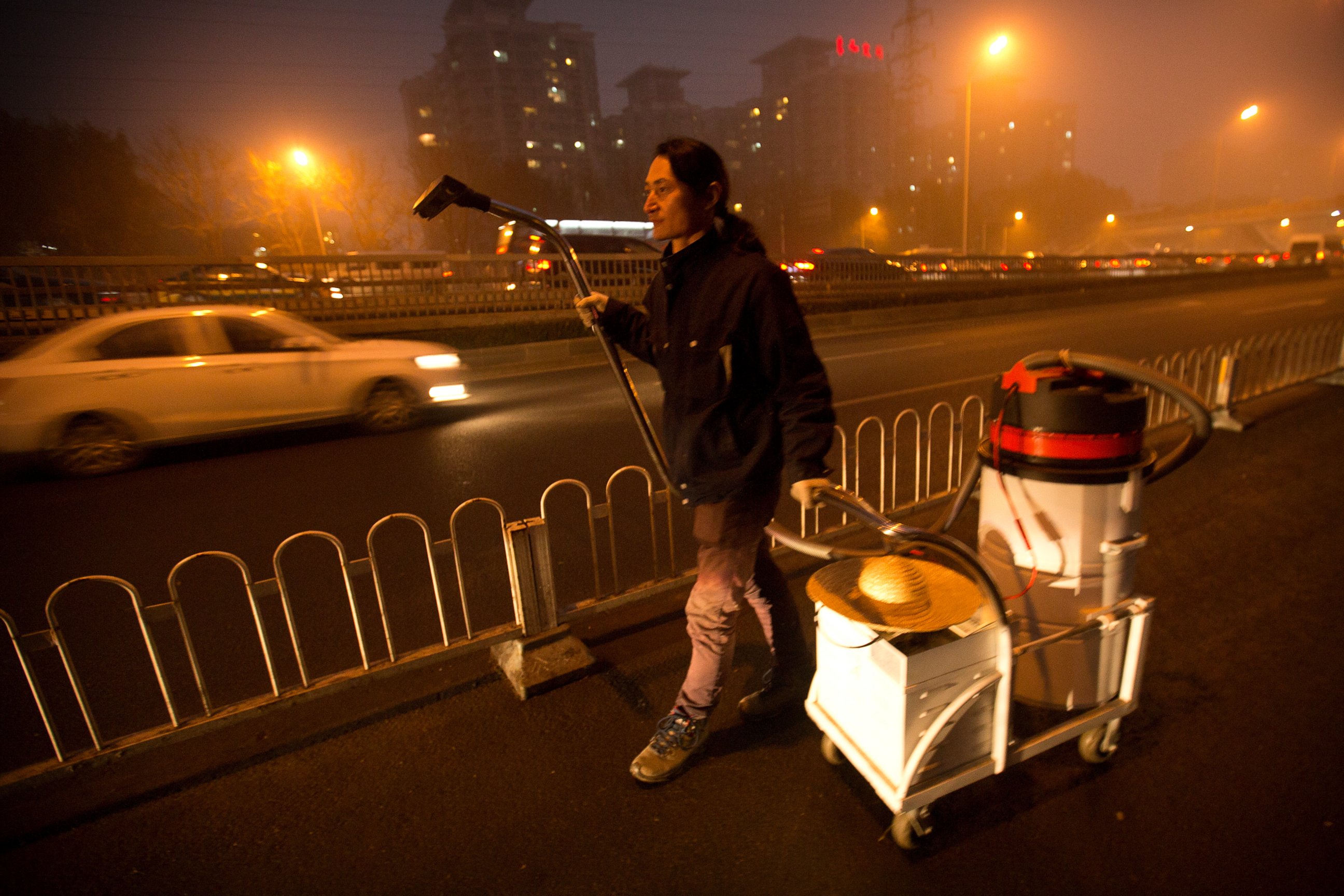 PHOTO: Chinese artist Wang Renzheng walks along a highway as he demonstrates the use of his industrial shop-vac in Beijing, Dec. 1, 2015.