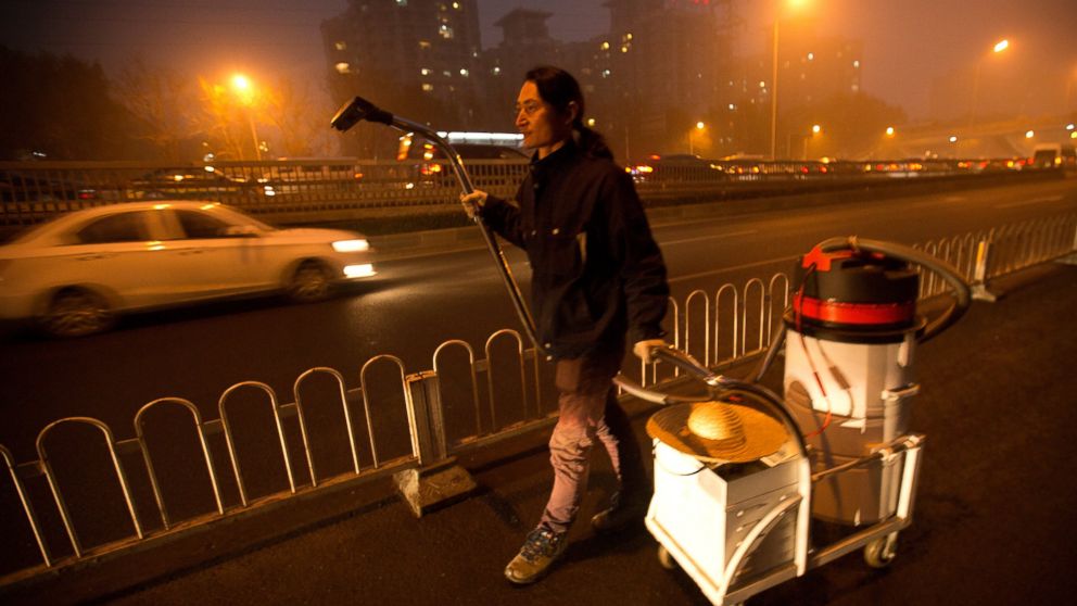 PHOTO: Chinese artist Wang Renzheng walks along a highway as he demonstrates the use of his industrial shop-vac in Beijing, Dec. 1, 2015.