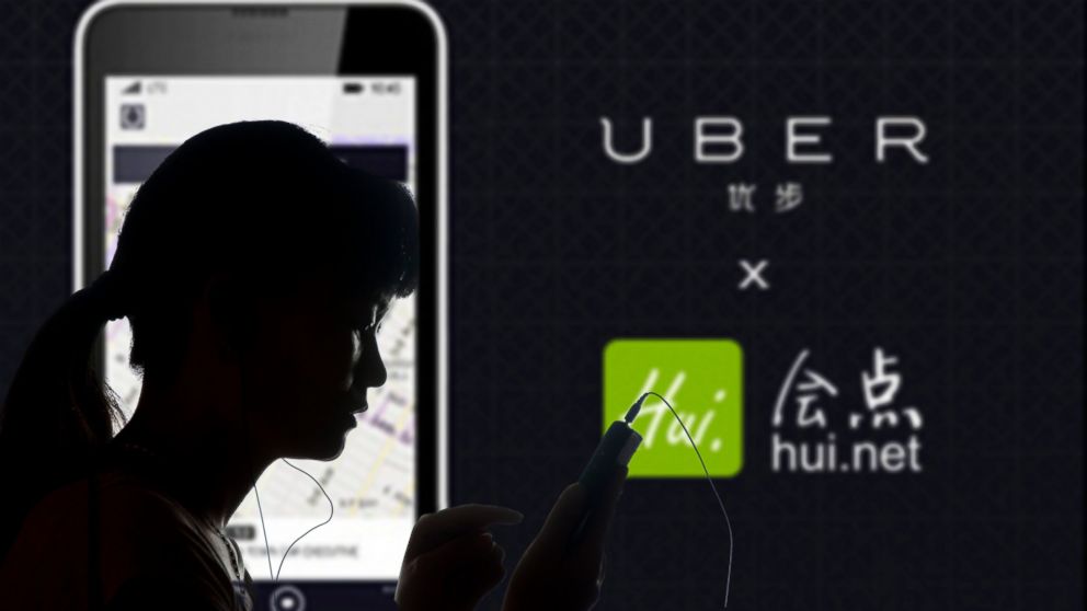 A woman uses her smartphone in front of an advertisement for taxi-hailing app Uber in Shaoyang city, central China's Hunan province, August 23, 2013.