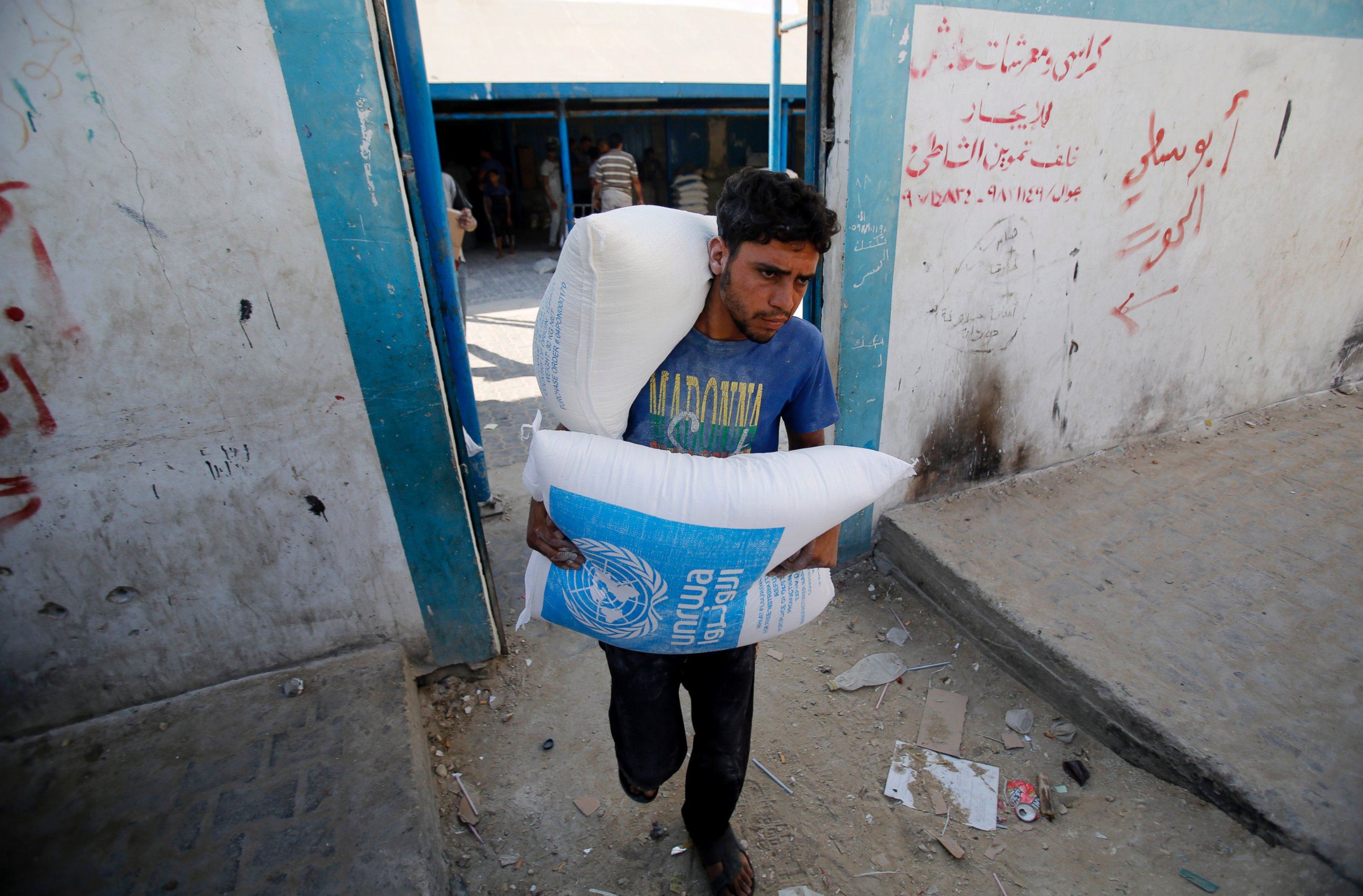 PHOTO: A Palestinian carries bags of flour at a United Nations food aid distribution center, in Shati refugee camp in Gaza City, Aug. 6, 2014. 