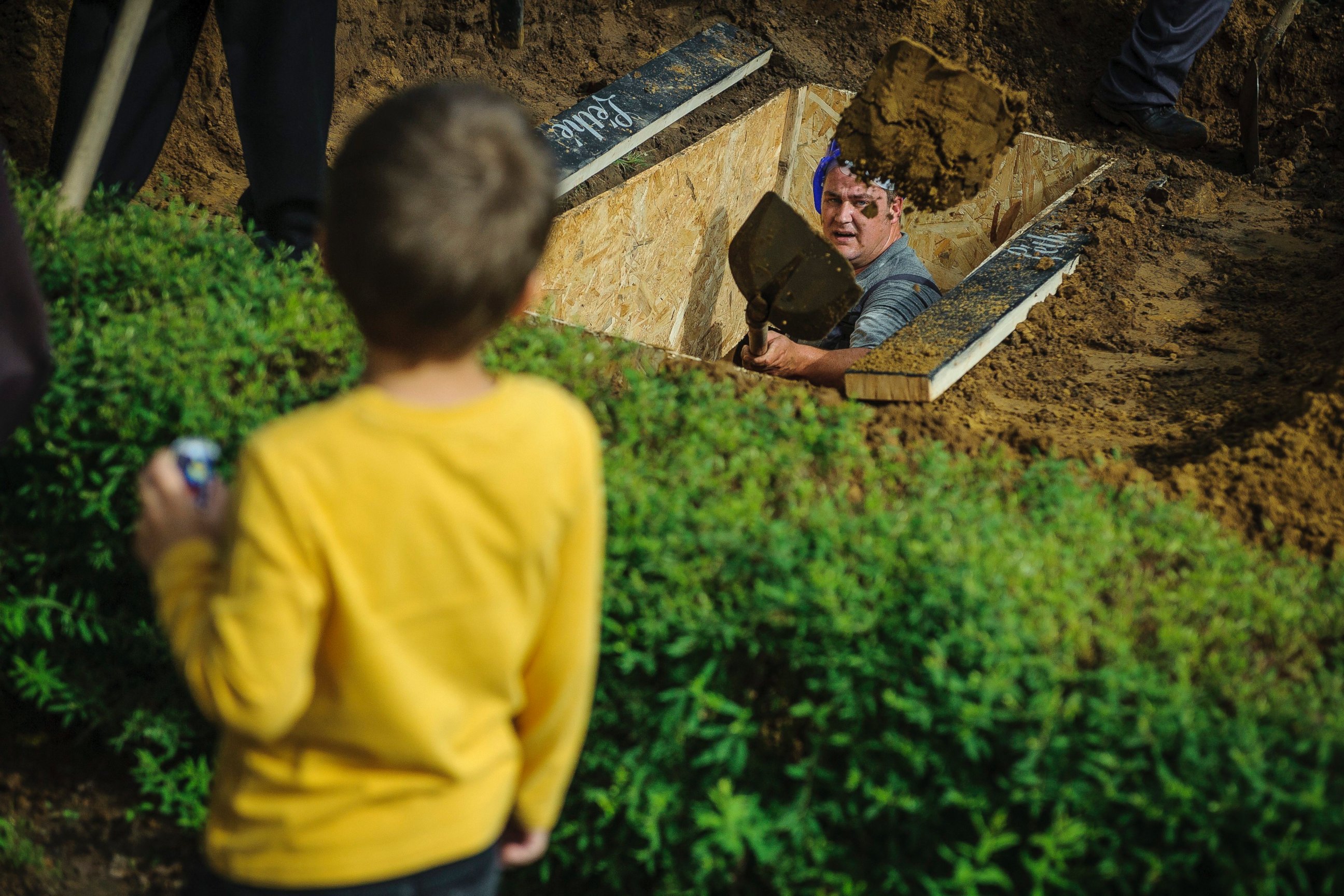 PHOTO: A gravedigger competes while a boy looks on during the first National Grave Digging competition at the public cemetery of Debrecen, Hungary, June 3, 2016.