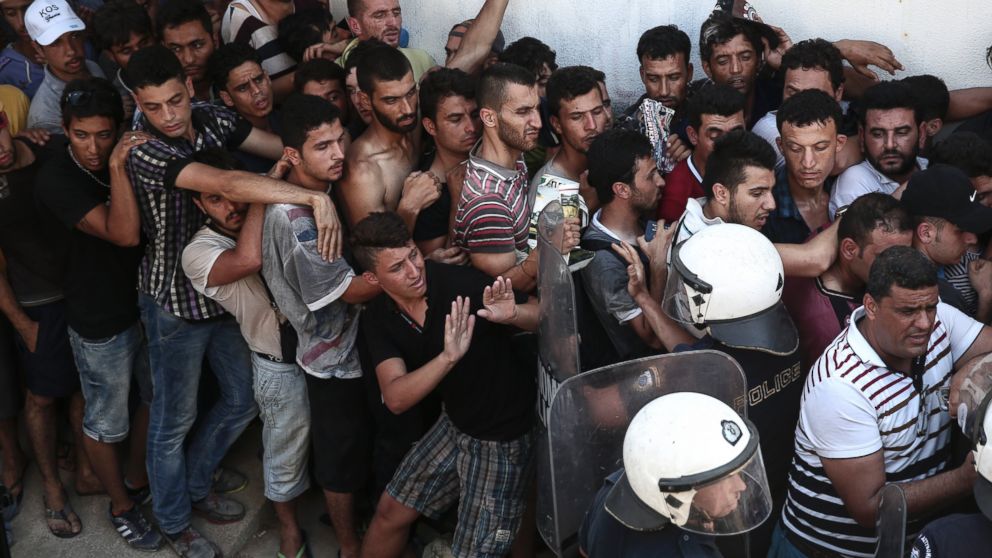 Police officers try to make space as migrants queuing for a registration procedure inside a stadium in Kos, on the Greek southeastern island of Kos, Aug. 12, 2015.