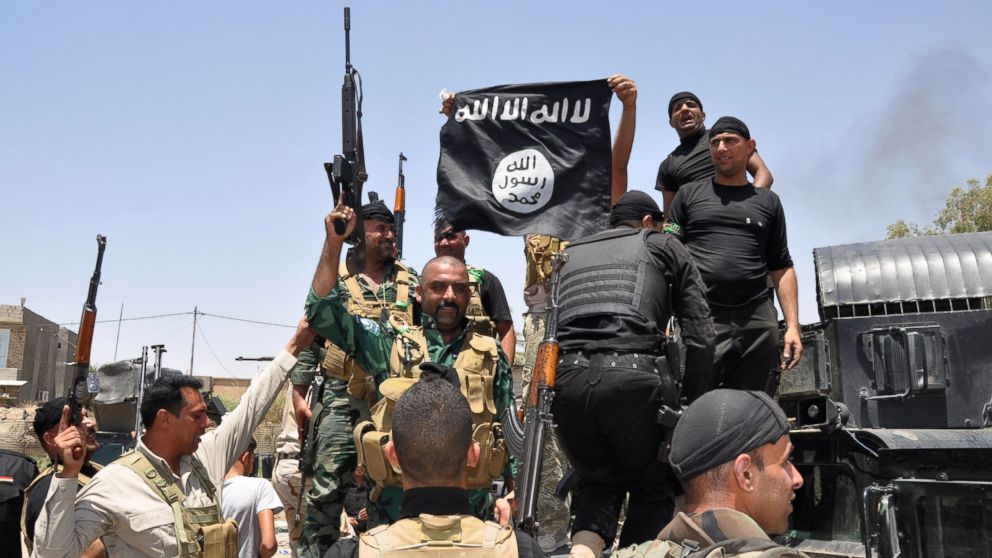 PHOTO: Iraqi security forces hold up a flag of the the jihadist group ISIS that they captured during an operation to regain control of Dallah Abbas, 35 miles outside of Baghdad, Iraq on Jun 28, 2014.
