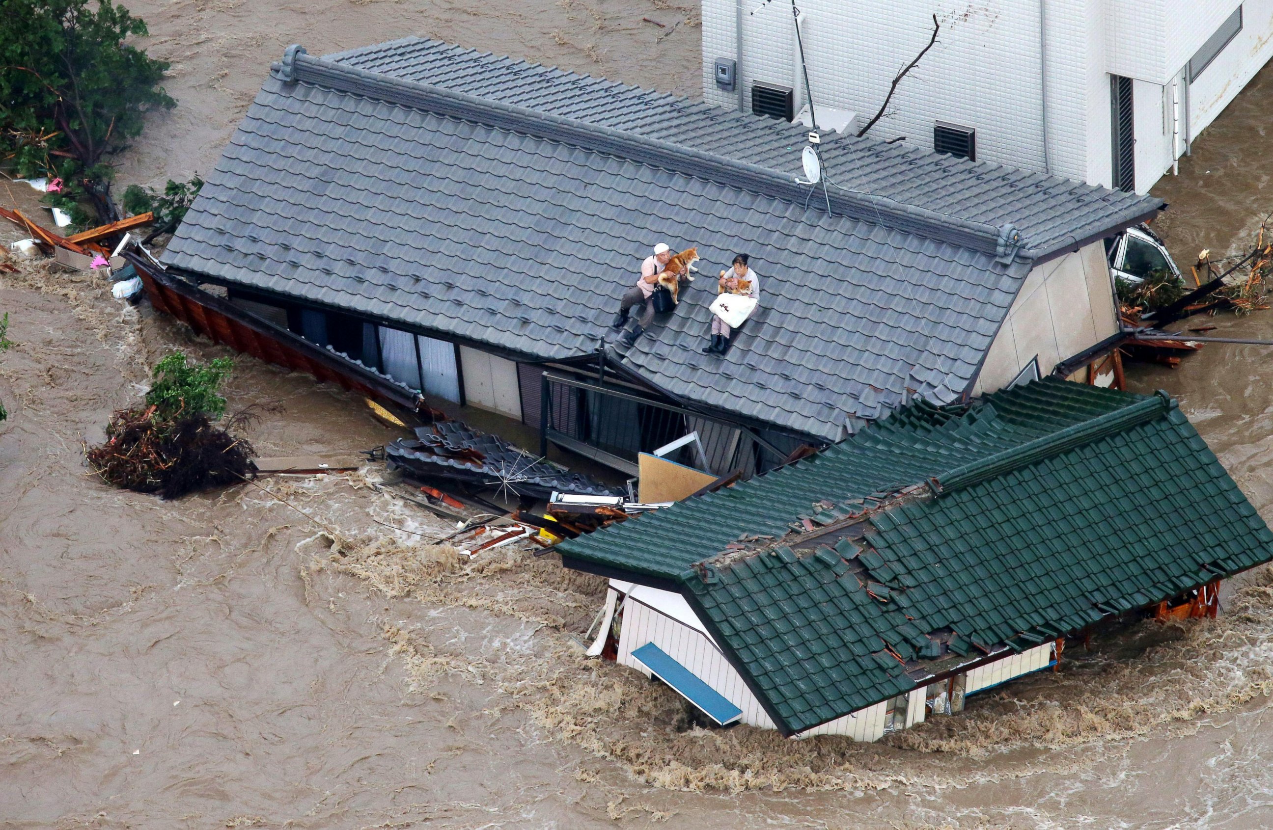 PHOTO: Residents holding dogs wait for help, sitting on the roof of their house in the flooded city of  Joso, Ibaraki prefecture, northeast of Tokyo, Sept. 10, 2015. 