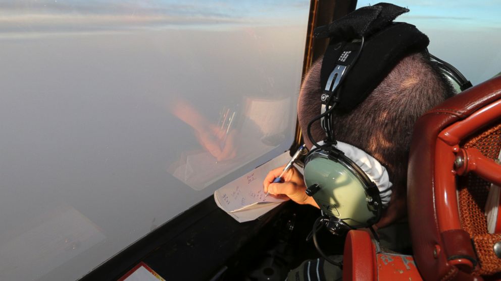 Flight Lt. Jason Nichols on board a Royal Australian Air Force AP-3C Orion, takes notes as they search for the missing Malaysia Airlines Flight MH370 in southern Indian Ocean, Australia, Saturday, March 22, 2014.