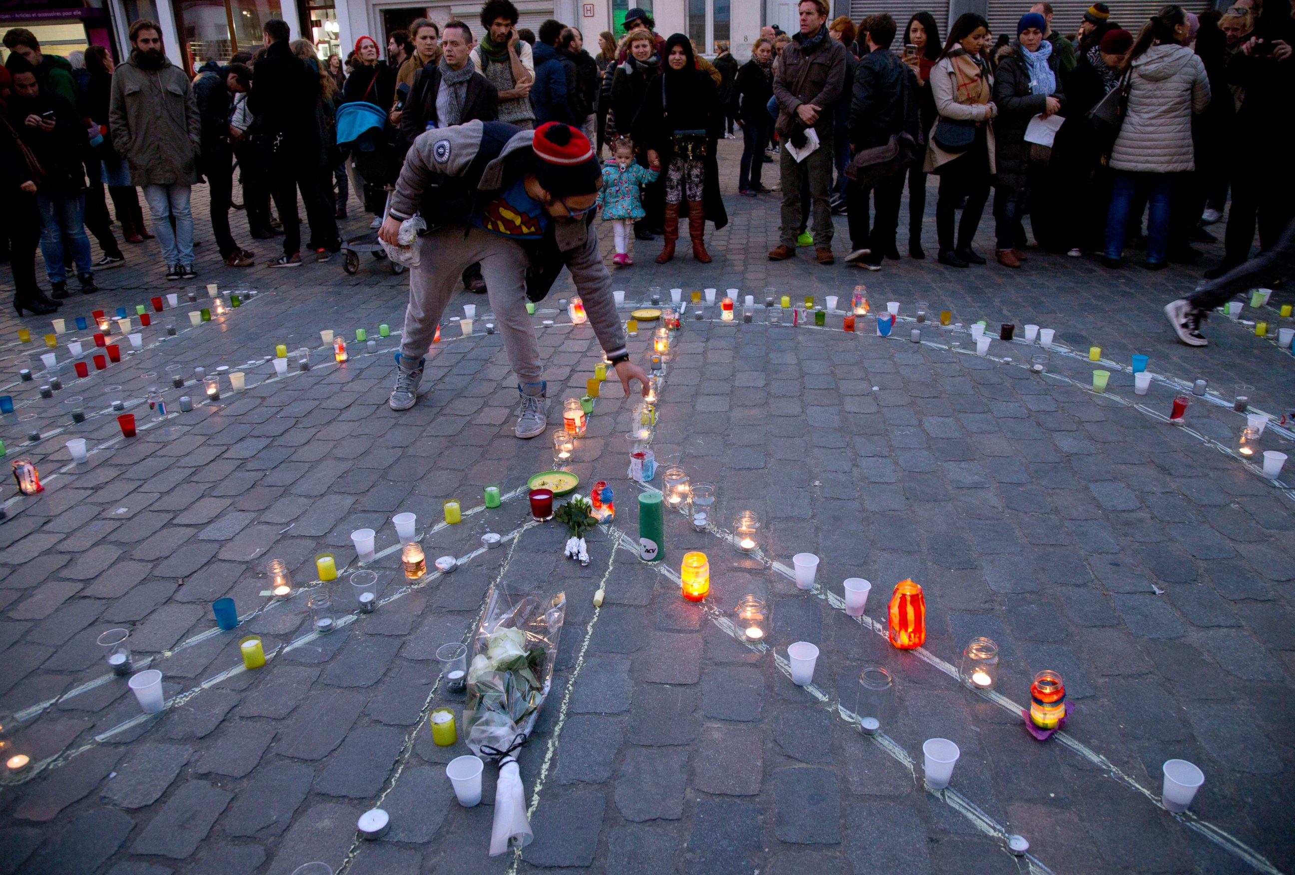 PHOTO: A man lights a candle which forms a peace sign during a candlelight vigil for the Paris attacks in the town square of Molenbeek, Belgium, Nov. 18, 2015. 
