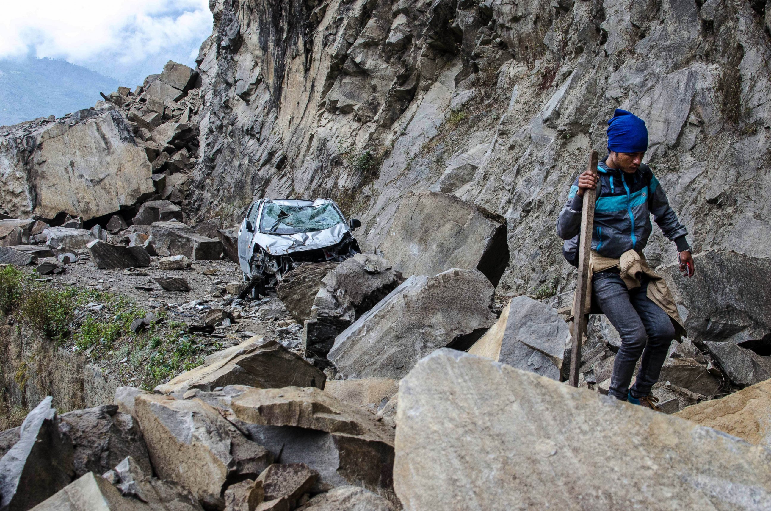 PHOTO: In this April 27, 2015 photo, a Nepalese man walks over fallen rocks and past a crushed car on the way to Dhunche, Nepal, a village in Langtang National Park, two days after a 7.8-magnatude earthquake hit the region.
