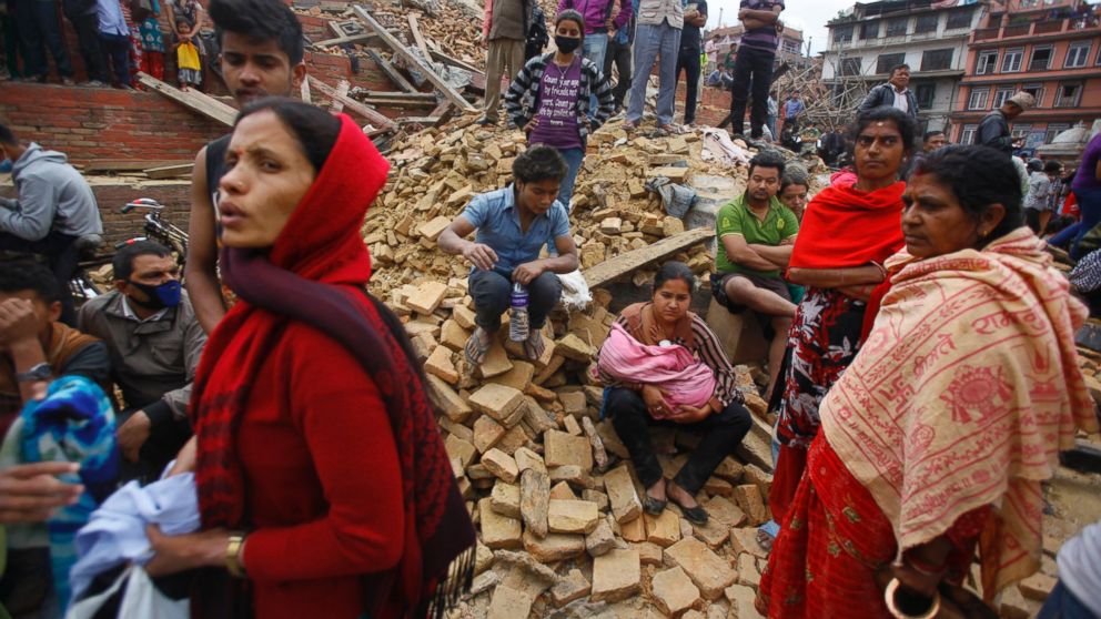 People rest on debris at Durbar Square after an earthquake in Kathmandu, Nepal, Saturday, April 25, 2015. A strong magnitude-7.9 earthquake shook Nepal's capital and the densely populated Kathmandu Valley before noon Saturday, causing extensive damage with toppled walls and collapsed buildings, officials said.