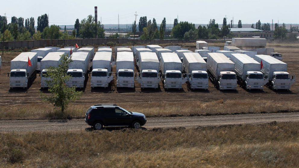A convoy of white trucks with humanitarian aid sits parked in a field about 28 kilometers from the Ukrainian border in Russia, on Aug. 14, 2014.