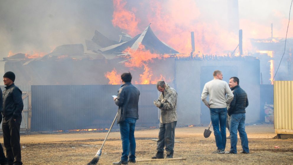 PHOTO: People watch burning houses in the village of Smolenka, Russia, April 13, 2015. 