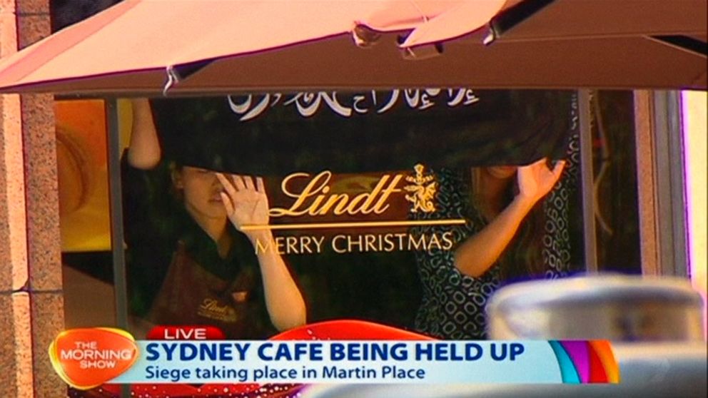 PHOTO: This image taken from video show people holding up what appeared to be a black flag with white Arabic writing on it, inside a cafe in Sydney, Australia, Dec. 15, 2014. 