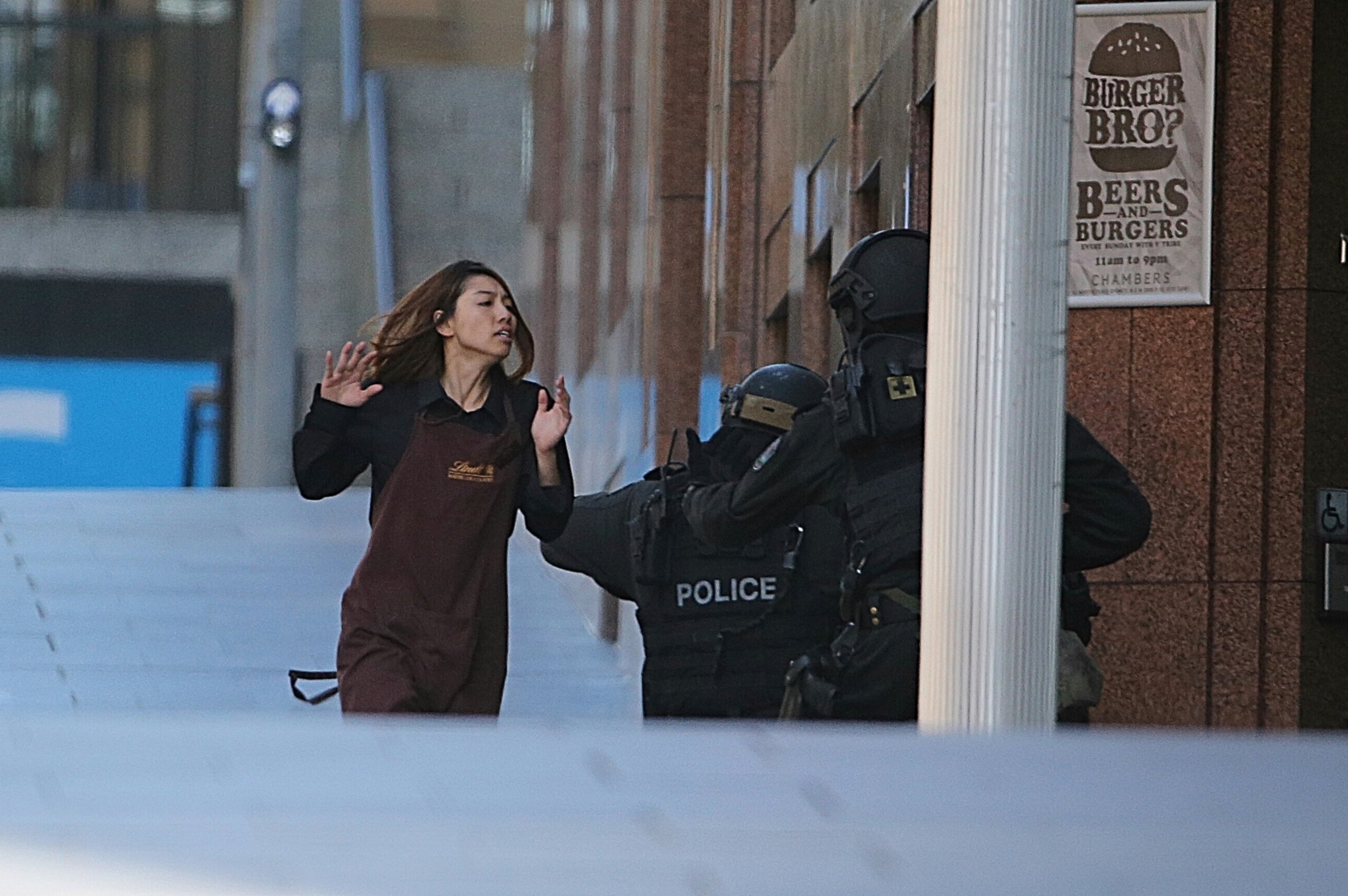 PHOTO: An armed tactical response police officer grabs a hostage as she flees from a cafe under siege at Martin Place in the central business district of Sydney, Australia, Dec. 15, 2014. 