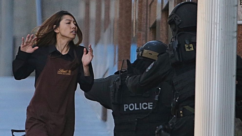 An armed tactical response police officer grabs a hostage as she flees from a cafe under siege at Martin Place in the central business district of Sydney, Australia, Dec. 15, 2014. 
