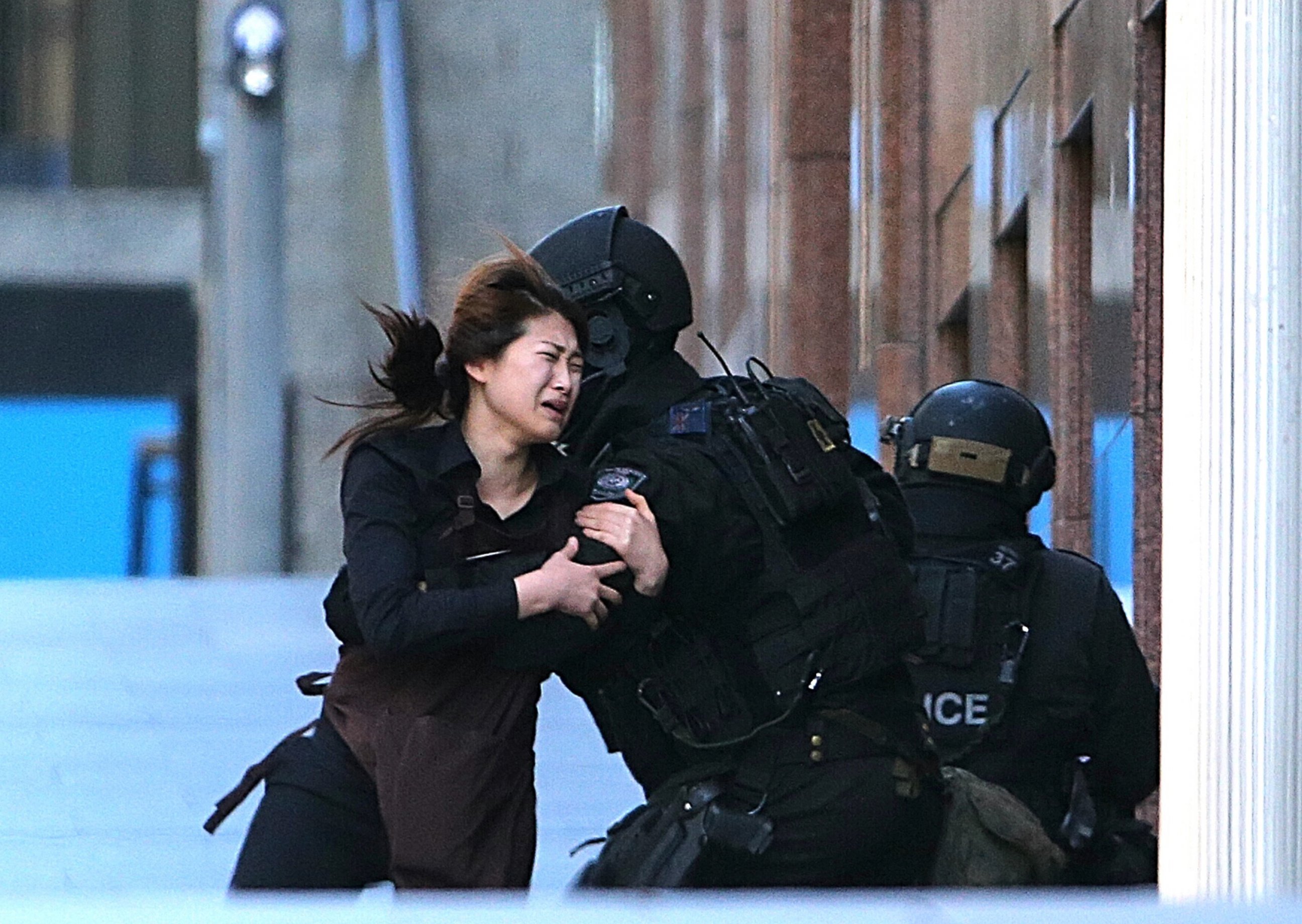 PHOTO: A hostage runs to armed tactical response police officers for safety after she escaped from a cafe under siege at Martin Place in the central business district of Sydney, Australia, Dec. 15, 2014. 