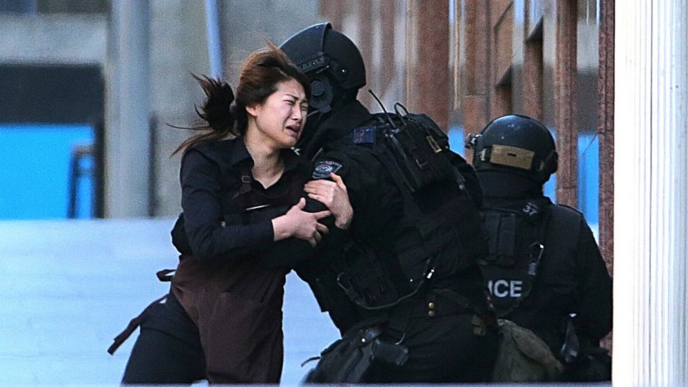 PHOTO: A hostage runs to armed tactical response police officers for safety after she escaped from a cafe under siege at Martin Place in the central business district of Sydney, Australia, Dec. 15, 2014. 