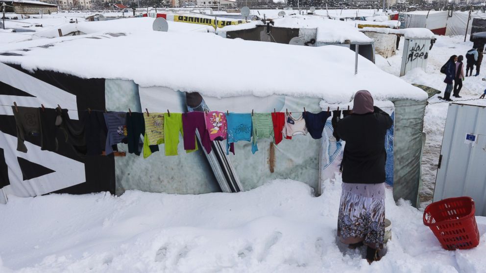 A Syrian woman hangs her laundry outside her tent covered by snow at a refugee camp in Zahleh town, Bekaa valley, east Lebanon, Jan. 8, 2015. 