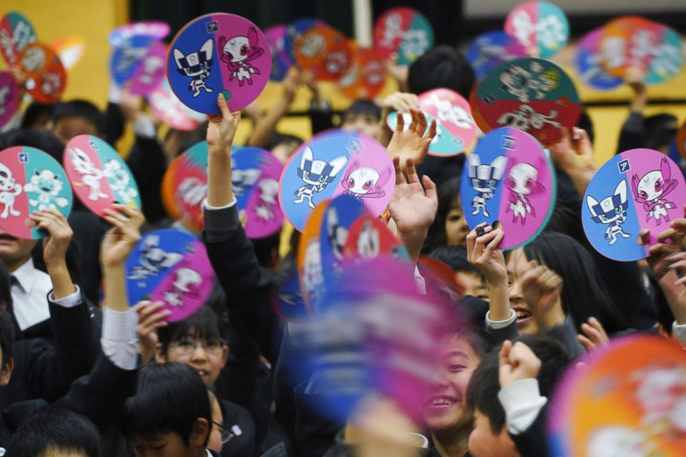 PHOTO: Students of a Tokyo school wave the fans with candidate characters printed on it as they wait for the characters which will serve as mascot for the Tokyo 2020 Olympic Games and Paralympics Games, are unveiled in Tokyo, Wednesday, Feb. 28, 2018.