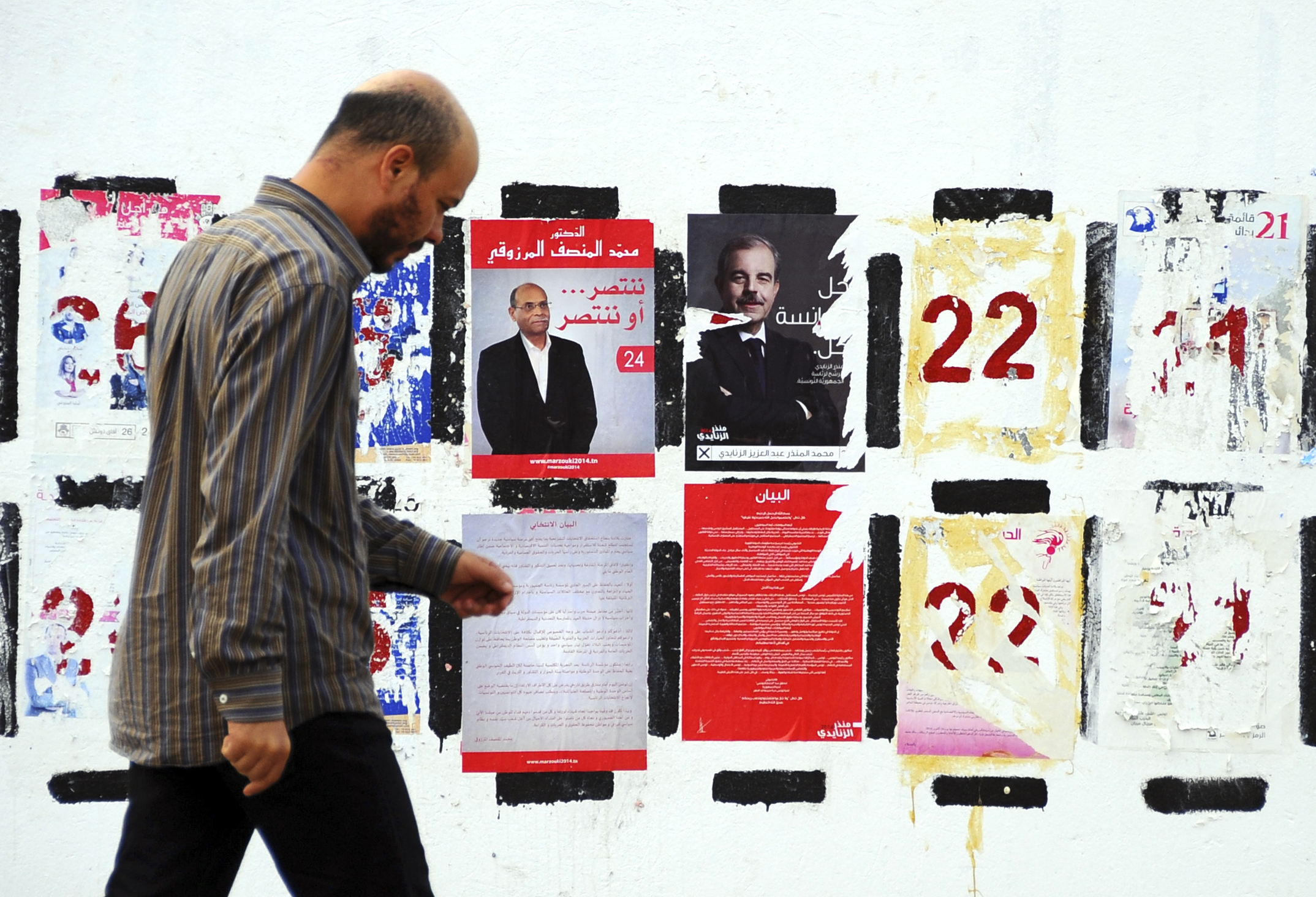 PHOTO: In this photo taken Nov. 5, 2014, a man walks past electoral posters for the upcoming presidential elections in Tunisia.