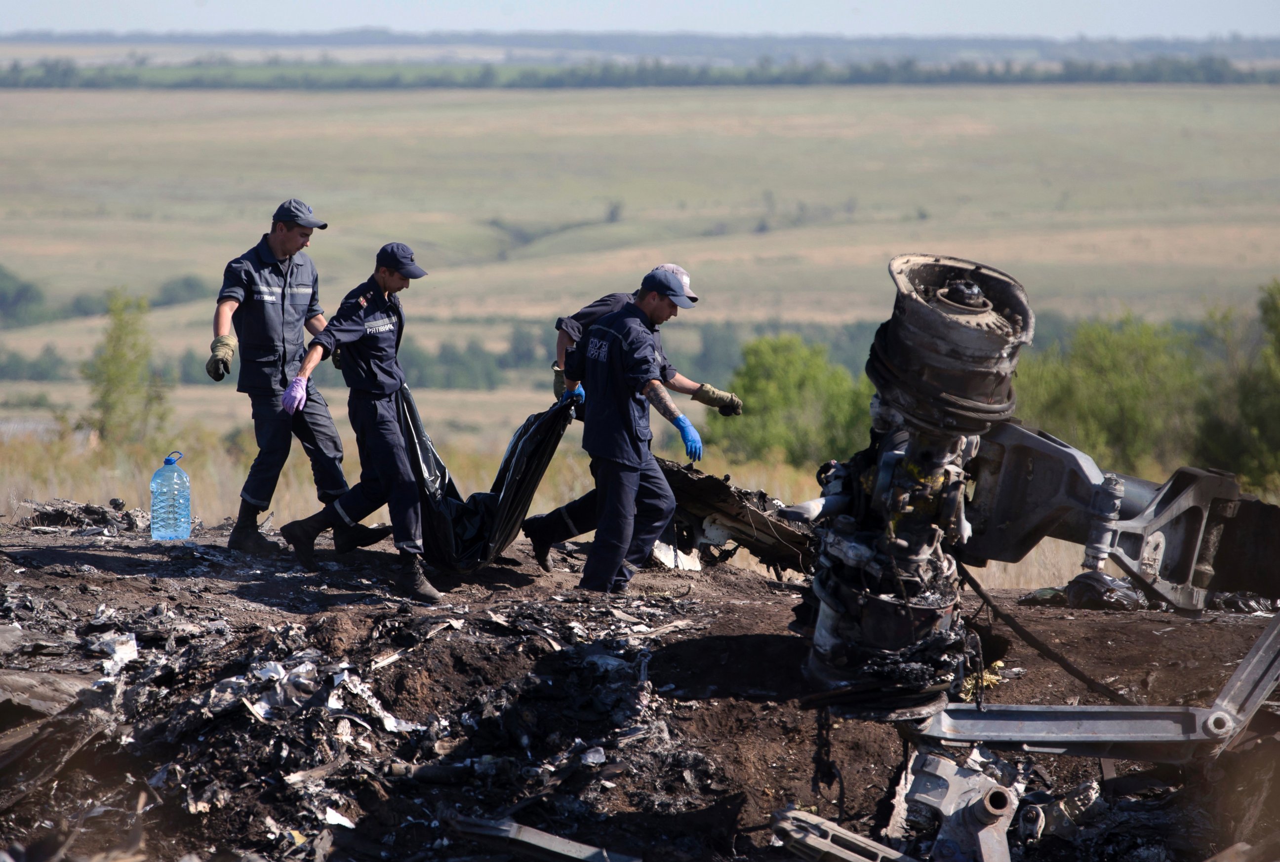 PHOTO: Ukrainian Emergency workers carry a victim's body in a plastic bag at the crash site of Malaysia Airlines Flight 17 near the village of Hrabove, Donetsk region, eastern Ukraine, July 21, 2014. 
