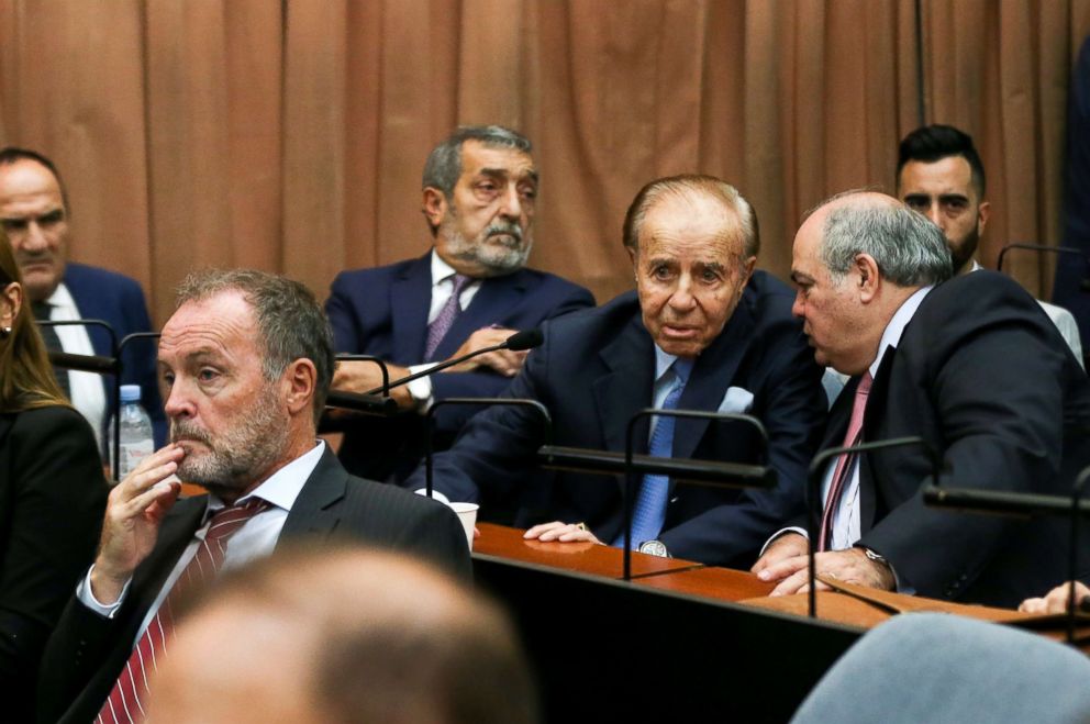 PHOTO: Former Argentine President Carlos Menem talks to an unidentified man behind former prosecutor Eamon Mullen before hearing the verdict in the trial of covering up the 1994 AMIA bombing, in Buenos Aires, Argentina. Feb. 28, 2019. 