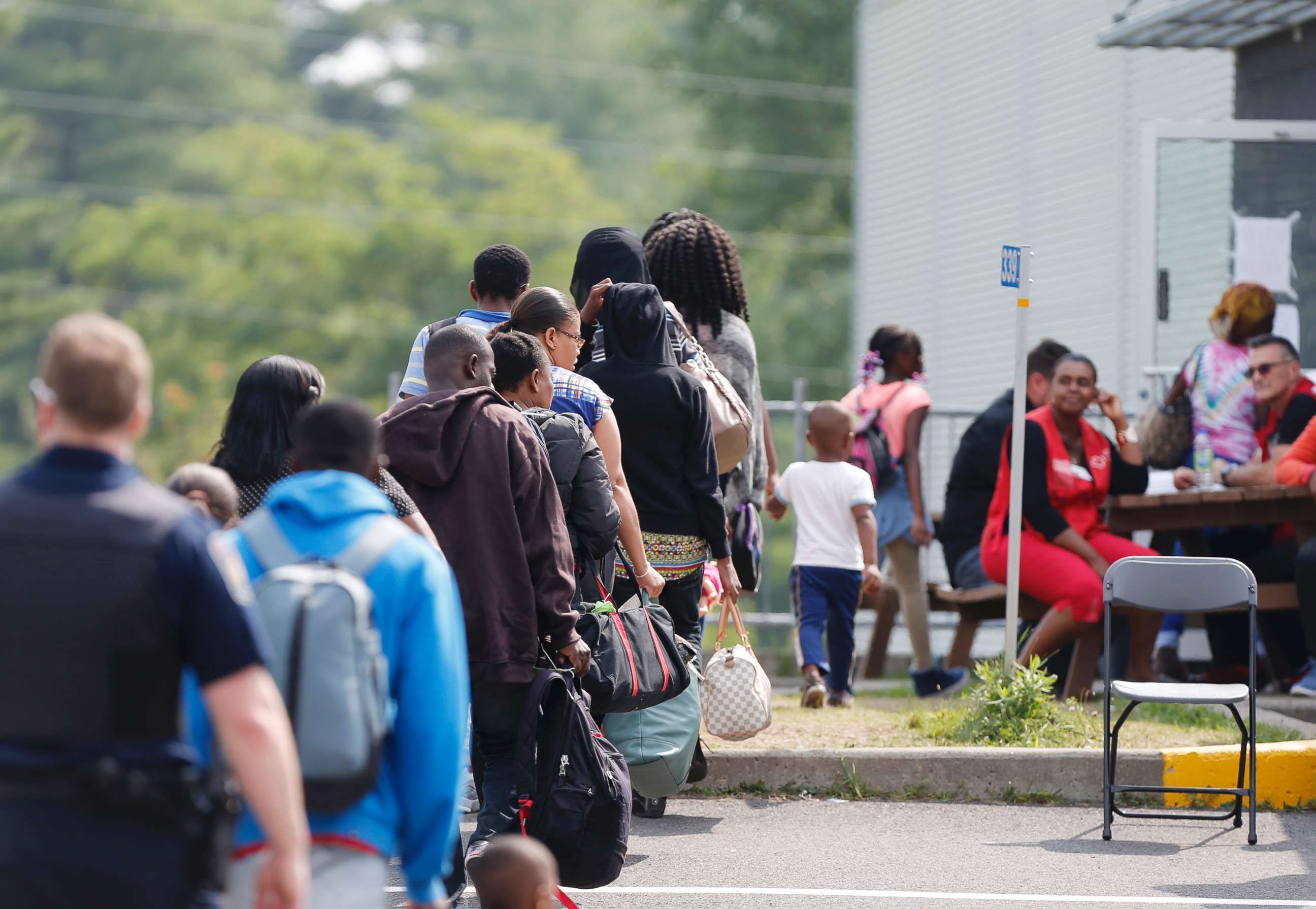PHOTO: A group of asylum seekers wait to be processed after being escorted from their tent encampment to the Canada Border Services in Lacolle, Quebec, on Aug. 11, 2017.
