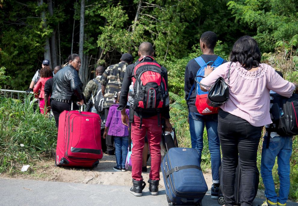 PHOTO: A group that stated they were from Haiti line up to cross the U.S.-Canada border into Hemmingford, Quebec, from Champlain in New York, Aug. 21, 2017.