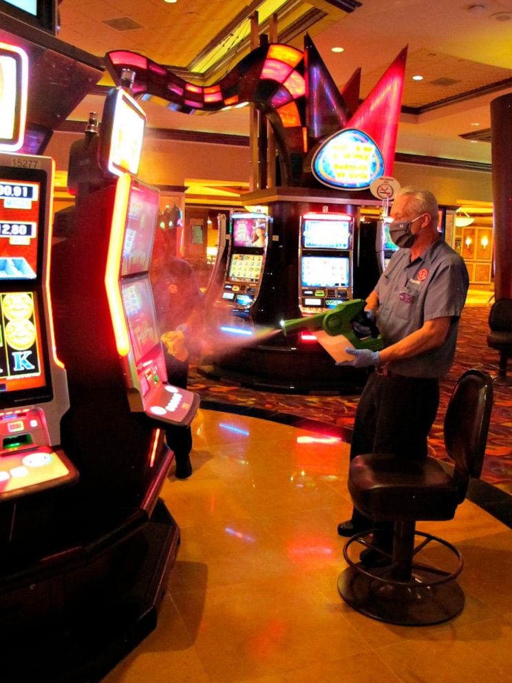 PHOTO: Steven Ford, a worker at Harrah's casino sprays slot machines with disinfectant in Atlantic City, N.J., July 1, 2020, as the casino prepared to reopen.