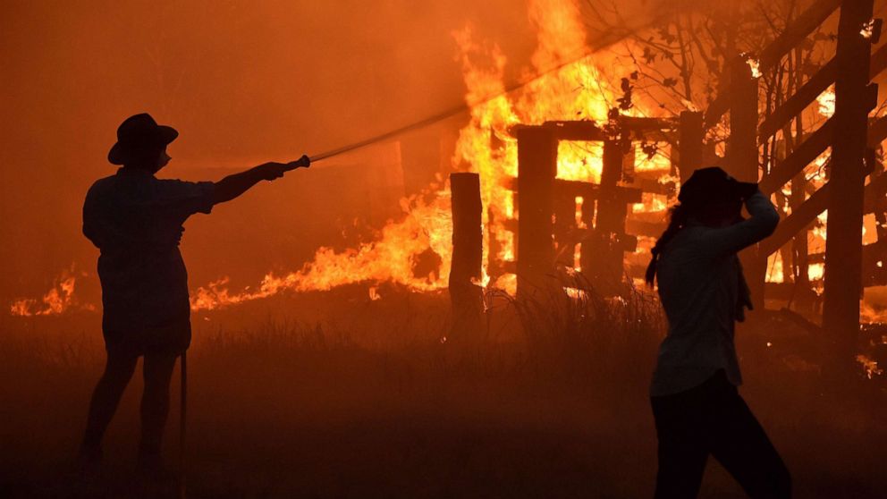 PHOTO: Residents defend a property from a bushfire at Hillsville near Taree, 350km north of Sydney on November 12, 2019. (Photo by PETER PARKS/AFP via Getty Images)