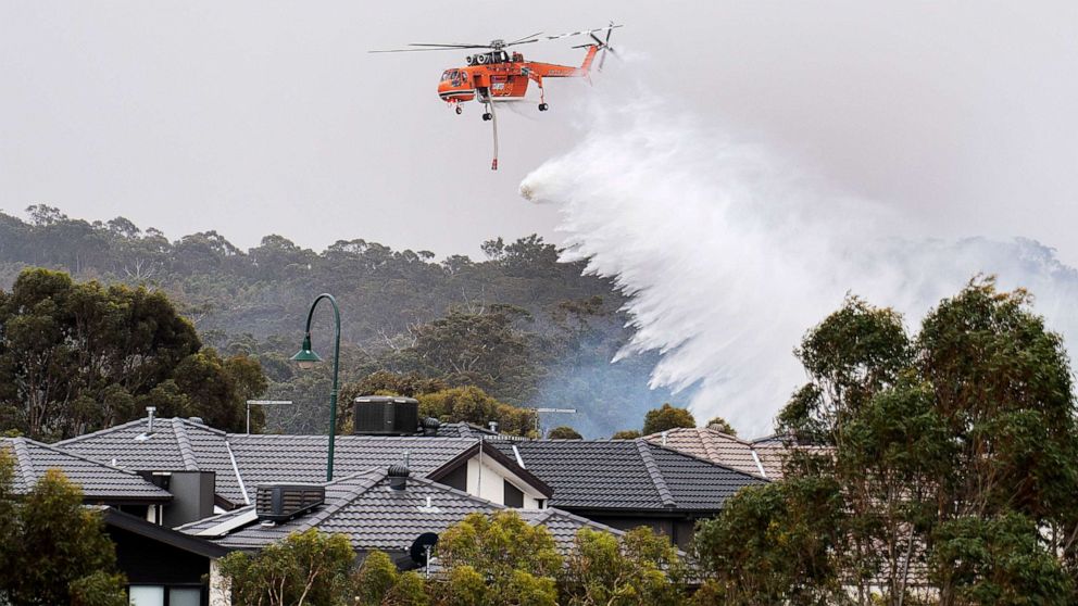 PHOTO: A skycrane drops water on a bushfire in scrub behind houses in Bundoora, Melbourne, Monday, Dec. 30, 2019.